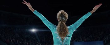 Movie still from “I, Tonya” (2017), directed by Craig Gillespie – A woman in a blue dress is holding her arms in the air; Medium shot, Low angle