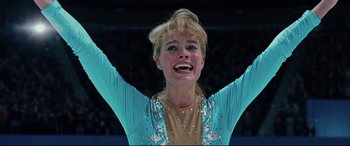 Movie still from “I, Tonya” (2017), directed by Craig Gillespie – A woman in a blue and tan outfit with her hands in the air; Close Up shot, Low angle