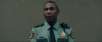Movie still from “I, Tonya” (2017), directed by Craig Gillespie – A man in a sheriff's uniform with a star badge; Close Up shot, Low angle