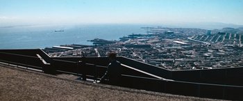 Movie still from “Dirty Harry” (1971), directed by Don Siegel – A man sitting on a bench looking over a city; Extreme Wide shot, High angle