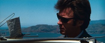 Movie still from “Dirty Harry” (1971), directed by Don Siegel – A person wearing sunglasses near a body of water; Close Up shot, Low angle