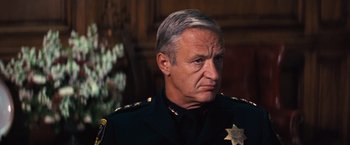 Movie still from “Dirty Harry” (1971), directed by Don Siegel – A man in a police officer's uniform looking to his left; Close Up shot, Low angle