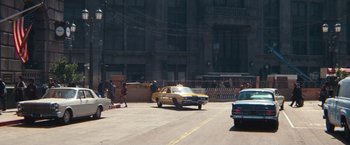 Movie still from “Dirty Harry” (1971), directed by Don Siegel – A taxi cab driving down a street past a tall building; Extreme Wide shot, High angle