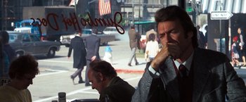 Movie still from “Dirty Harry” (1971), directed by Don Siegel – Two men on a street with a crowd of people walking on the sidewalk behind them; Medium shot, Over the shoulder angle