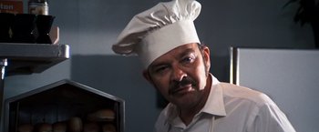 Movie still from “Dirty Harry” (1971), directed by Don Siegel – A man wearing a chef's hat in front of a counter; Close Up shot, Low angle