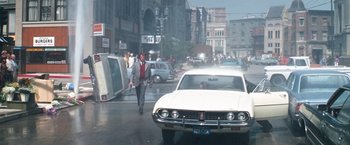 Movie still from “Dirty Harry” (1971), directed by Don Siegel – A man walking down a street next to a white car; Wide shot, Low angle