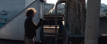 Movie still from “Dirty Harry” (1971), directed by Don Siegel – A man holding a gun on top of a building; Medium shot, Low angle