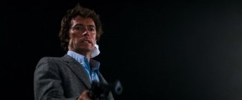 Movie still from “Dirty Harry” (1971), directed by Don Siegel – A man holding a gun while wearing a jacket; Close Up shot, Low angle