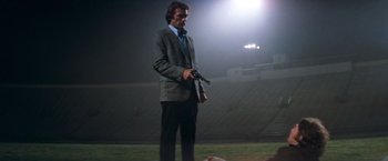 Movie still from “Dirty Harry” (1971), directed by Don Siegel – A man in a suit and tie holding a gun in his hand; Wide shot, Low angle
