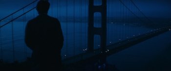 Movie still from “Dirty Harry” (1971), directed by Don Siegel – A man standing in front of the golden gate bridge at night; Extreme Wide shot, Low angle