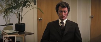 Movie still from “Dirty Harry” (1971), directed by Don Siegel – A person wearing a suit and tie; Medium shot, Over the shoulder angle