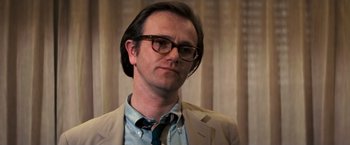 Movie still from “Dirty Harry” (1971), directed by Don Siegel – A man in a suit and tie wearing glasses; Close Up shot, Low angle