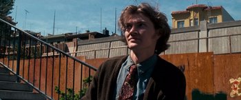 Movie still from “Dirty Harry” (1971), directed by Don Siegel – A man wearing a tie standing outside in the sun; Close Up shot, Low angle