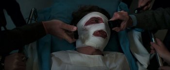 Movie still from “Dirty Harry” (1971), directed by Don Siegel – A man with bandages on his face is laying in a bed; Close Up shot, High angle