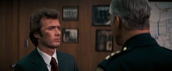 Movie still from “Dirty Harry” (1971), directed by Don Siegel – A man in a suit and tie standing next to another man in a suit and tie; Close Up shot, Over the shoulder angle