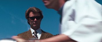 Movie still from “Dirty Harry” (1971), directed by Don Siegel – A man in a suit and tie standing next to another man in a suit; Close Up shot, Low angle