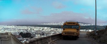 Movie still from “Dirty Harry” (1971), directed by Don Siegel – A yellow school bus driving down a street; Extreme Wide shot, High angle
