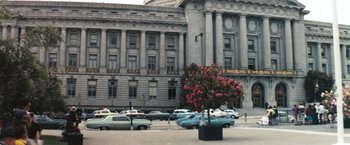 Movie still from “Dirty Harry” (1971), directed by Don Siegel – A tree in the middle of a street with cars parked in front of it; Extreme Wide shot, High angle
