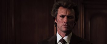 Movie still from “Dirty Harry” (1971), directed by Don Siegel – A person wearing a suit and tie; Close Up shot, Low angle