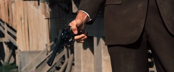 Movie still from “Dirty Harry” (1971), directed by Don Siegel – A man in a black suit holding a gun in his right hand; Close Up shot, Overhead angle