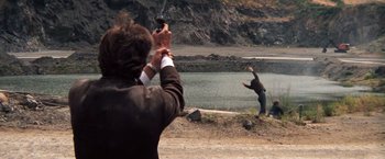 Movie still from “Dirty Harry” (1971), directed by Don Siegel – A man holding a gun while standing next to another man; Wide shot, Over the shoulder angle