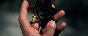 Movie still from “Dirty Harry” (1971), directed by Don Siegel – A person holding a badge in their hand; Extreme Close Up shot, High angle