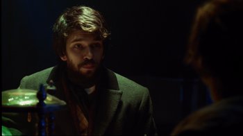 Movie still from “In the Heart of the Sea” (2015), directed by Ron Howard – A man with a beard wearing a suit and tie; Medium shot, Over the shoulder angle