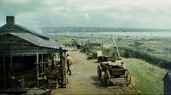 Movie still from “In the Heart of the Sea” (2015), directed by Ron Howard – A man walking down a dirt road next to a cart; Extreme Wide shot, High angle