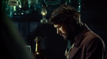 Movie still from “In the Heart of the Sea” (2015), directed by Ron Howard – A man looking down at a bottle of beer; Close Up shot, Over the shoulder angle