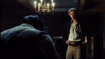 Movie still from “In the Heart of the Sea” (2015), directed by Ron Howard – A man standing next to a chandelier in a room; Medium shot, Over the shoulder angle