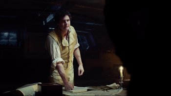 Movie still from “In the Heart of the Sea” (2015), directed by Ron Howard – A man standing in front of papers and a candle; Medium shot, Over the shoulder angle