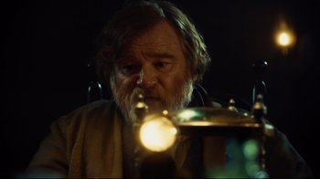 Movie still from “In the Heart of the Sea” (2015), directed by Ron Howard – An old man with a beard and a mustache is looking at a lamp; Close Up shot, Over the shoulder angle