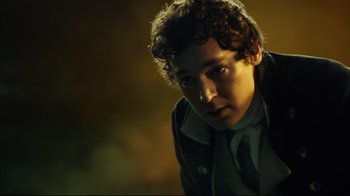 Movie still from “In the Heart of the Sea” (2015), directed by Ron Howard – A man with curly brown hair wearing a jacket and a tie; Close Up shot, Low angle