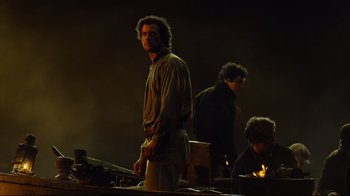 Movie still from “In the Heart of the Sea” (2015), directed by Ron Howard – A man standing in front of a fire pit; Medium shot, Low angle