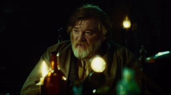 Movie still from “In the Heart of the Sea” (2015), directed by Ron Howard – An older man sitting in front of a bottle of wine; Medium shot, Over the shoulder angle
