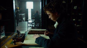 Movie still from “In the Heart of the Sea” (2015), directed by Ron Howard – A young man writing on a piece of paper; Medium shot, Low angle