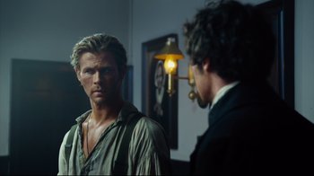 Movie still from “In the Heart of the Sea” (2015), directed by Ron Howard – A man standing in front of a mirror next to another man; Medium shot, Over the shoulder angle