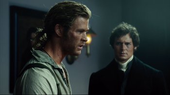 Movie still from “In the Heart of the Sea” (2015), directed by Ron Howard – Two men are standing next to each other in a room; Medium shot, Over the shoulder angle
