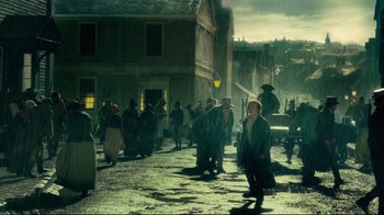 Movie still from “In the Heart of the Sea” (2015), directed by Ron Howard – A group of people walking down a street in the rain; Wide shot, High angle