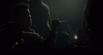 Movie still from “Inside Llewyn Davis” (2013), directed by Ethan Coen – A man sitting at a table with a cigarette in his mouth; Medium shot, Over the shoulder angle