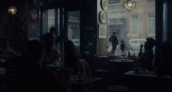 Movie still from “Inside Llewyn Davis” (2013), directed by Ethan Coen – People are sitting at tables in front of a window; Wide shot, Over the shoulder angle