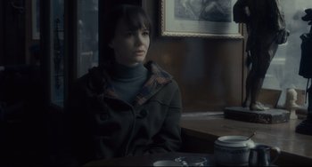 Movie still from “Inside Llewyn Davis” (2013), directed by Ethan Coen – A woman sitting at a table in front of a painting; Medium shot, Over the shoulder angle