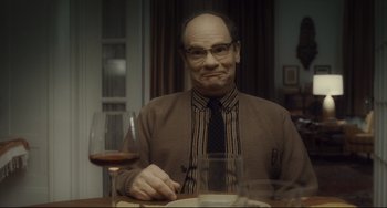 Movie still from “Inside Llewyn Davis” (2013), directed by Ethan Coen – A man sitting at a table with a glass of wine; Medium shot, Over the shoulder angle