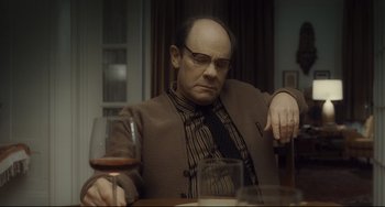 Movie still from “Inside Llewyn Davis” (2013), directed by Ethan Coen – A man sitting at a table with a glass of wine; Medium shot, High angle