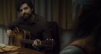 Movie still from “Inside Llewyn Davis” (2013), directed by Ethan Coen – A man sitting at a table playing a guitar; Close Up shot, Over the shoulder angle