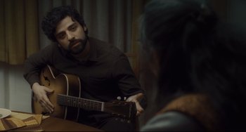 Movie still from “Inside Llewyn Davis” (2013), directed by Ethan Coen – A man sitting in front of a woman playing a guitar; Close Up shot, Over the shoulder angle