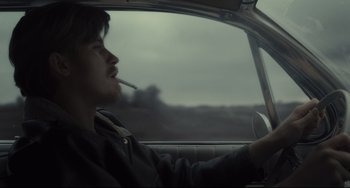 Movie still from “Inside Llewyn Davis” (2013), directed by Ethan Coen – A man sitting in the drivers seat of a car while smoking a cigarette; Medium shot, Over the shoulder angle
