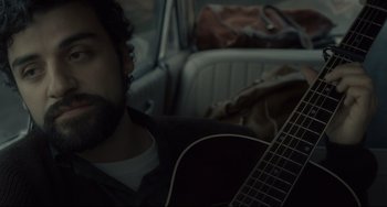 Movie still from “Inside Llewyn Davis” (2013), directed by Ethan Coen – A man sitting in the back of a car with a guitar; Close Up shot, Over the shoulder angle