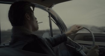 Movie still from “Inside Llewyn Davis” (2013), directed by Ethan Coen – A man sitting in the drivers seat of a car while smoking a cigarette; Medium shot, Over the shoulder angle