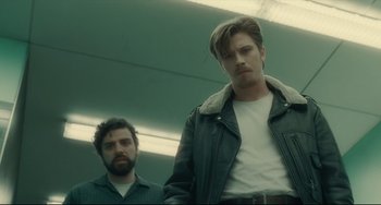 Movie still from “Inside Llewyn Davis” (2013), directed by Ethan Coen – Two men standing next to each other in front of a green wall; Medium shot, Low angle